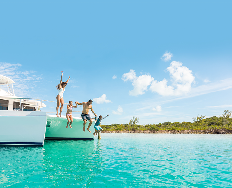 Kids jumping from a catamaran into turquoise water